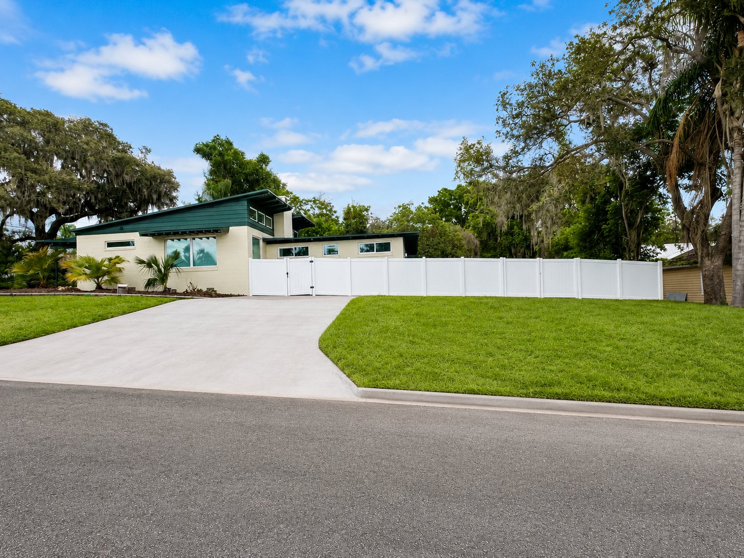 The house from the street: butterfly roof, deep green fascia and a clerestory window band